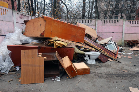 旧家具成堆倾倒在垃圾桶和白色马桶里图片