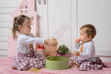两个姐妹1岁和3岁女孩坐在厨房的地板上玩干意面图片