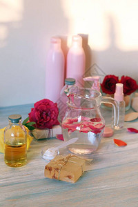 桌上的新鲜玫瑰花瓣水和油图片
