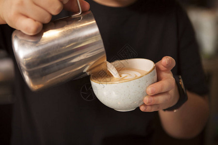 在咖啡杯里加热牛奶准备美味的卡布奇诺图片