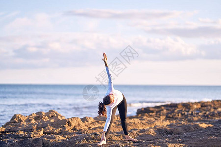 年轻美丽的女青年在做瑜伽教练在沙图片