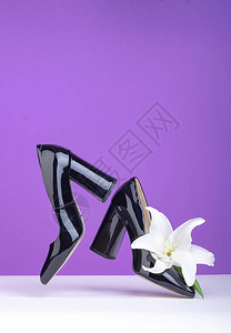 飞舞的黑色皮革专利皮鞋白百合花白色紫罗兰背景横幅与复制空间图片