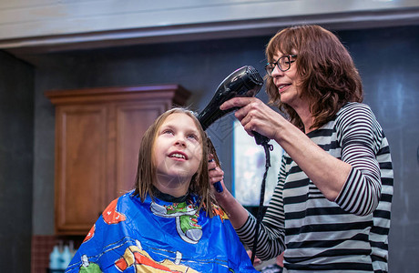 发型师用吹风机和梳子来给年轻女图片