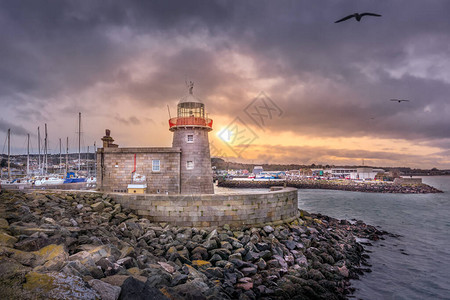 霍斯灯塔与在美丽的日落时飞翔的海鸥爱尔兰都柏林港口图片