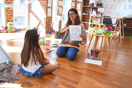 美丽的生理学家和幼童在幼儿园的很多玩具周围进行情绪化疗背景图片