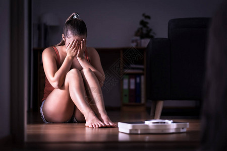 对减肥节食或体重增加有压力的女饮食失调厌食症或贪食症的概念年轻的女孩哭着坐在地板上图片