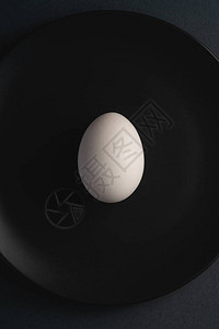 黑盘中的单白蛋在深沉的情调平淡的最起码背景最顶端景色复图片