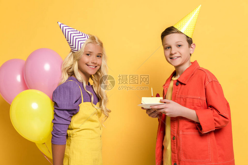 带着盛装着气球和盘子的派对帽戴着黄背景生日蛋图片