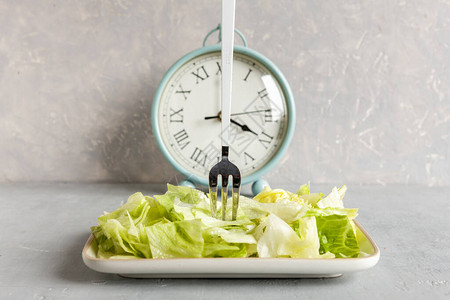 闹钟和绿色冰山生菜盘子间歇节食概念诱背景图片