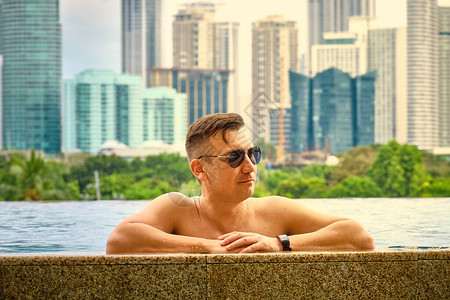 一个人在酒店屋顶的游泳池里从豪华的五星级DiscoveryPrimea酒店的游泳池欣赏马尼拉市的景色天气晴朗背景图片