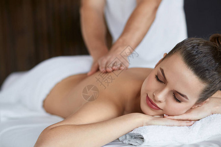 年轻漂亮的女人在水疗中心享受背部和肩部按摩专业按摩治疗师正在公寓里治疗一名女患者放松美容身体和面部治疗概图片
