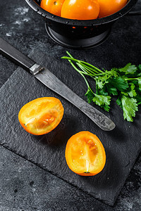 新鲜黄番茄切成两半黑色背图片