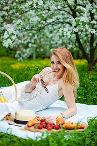 在盛开的果园野餐时身着白礼服和太阳镜的图片
