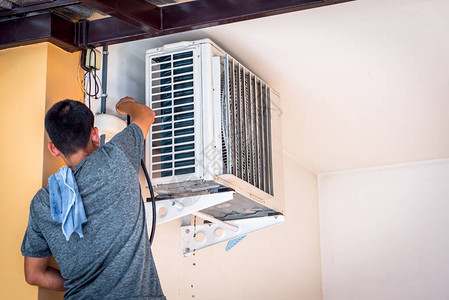 空调清洗维修服务时工人用水清洗空调盘管冷却器以清洁客户背景