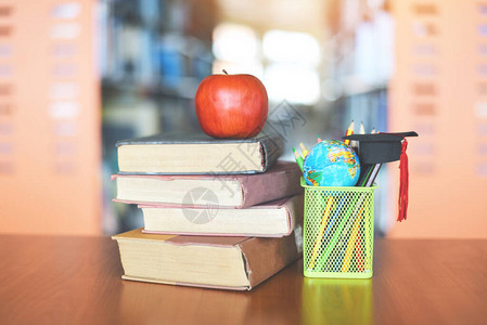 图书馆桌上的书教育学习旧书堆和毕业帽在铅笔盒上图片