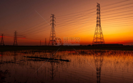 高压电塔和电线与夕阳的天空电线杆电力和能源的概念工业厂附近稻田图片