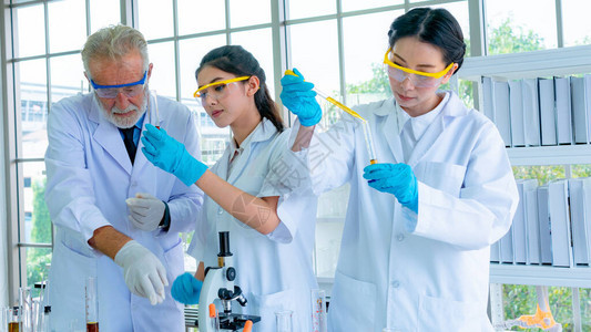 一组身着白袍的教授研究员科学家准备用桌上的科学设备测试化学液体用脸集中与背景内图片