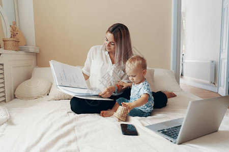 年轻母亲及其孩子在家卧室工作图片