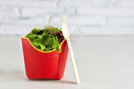 绿色沙拉在一次生态友好食品包装中配有叉子图片
