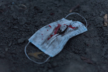 一个带血的医用口罩躺在地上背景图片