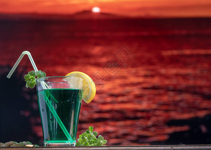 绿色鸡尾酒在一个玻璃杯子上在前景的一幅奇图片