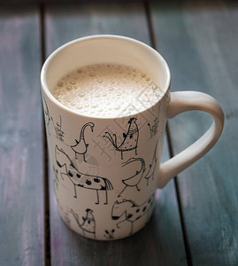 咖啡和牛奶在高白杯的牛奶与一幅动物图画紧贴图片