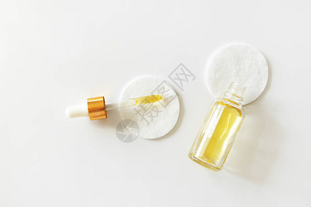 玻璃瓶中的油血清润湿剂和白色背景的棉垫上的水管图片