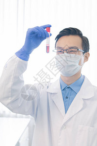 白外套手套面罩和眼镜的快乐青年药剂师在实验室工作时图片