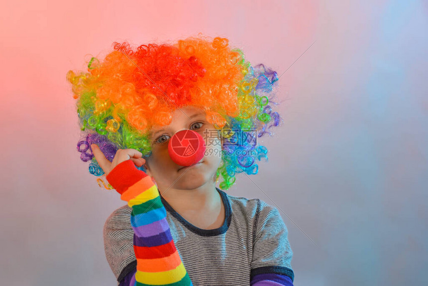 带着小丑假发和红鼻子的欢乐男孩将他的图片