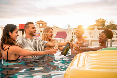 快乐的朋友在泳池派对上举杯庆祝年轻人在日落时在豪华热带度假村喝起泡酒玩得开心暑假和期青年图片
