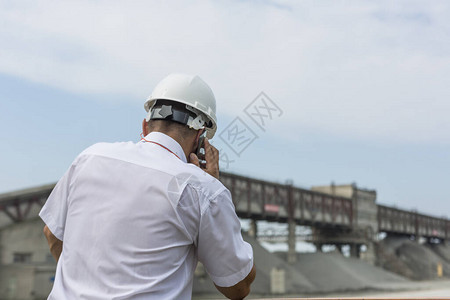白衬衫和戴头盔的采矿工程师持有电话图片