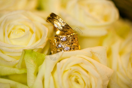在婚礼当天关闭两个结婚戒指和白色的婚礼花束图片