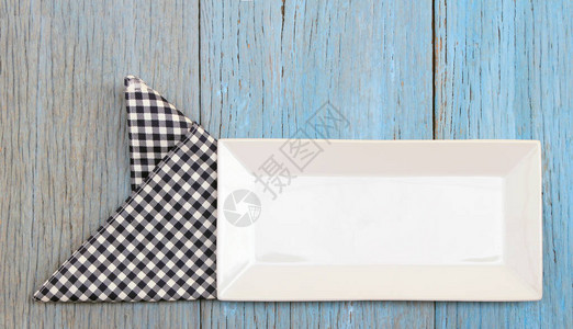 木桌背景上桌布上的白盘子图片