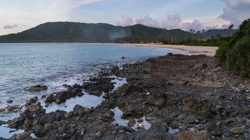 菲律宾帕拉万州埃尔尼多附近的纳克潘海滩火山岩滩云层和棕榈树边海图片