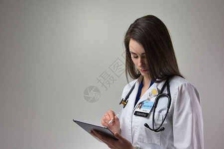 女人在平板电脑上为医院的病人护理做笔记图片