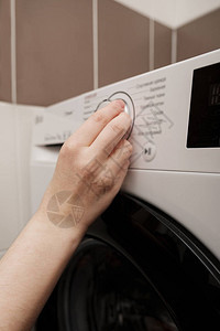 洗衣房里的家庭主妇在洗衣机上选择循环程序用洗衣机洗衣服关闭女人图片