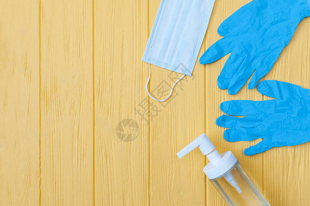 洗涤剂瓶呼吸面罩和黄色背景的手套图片