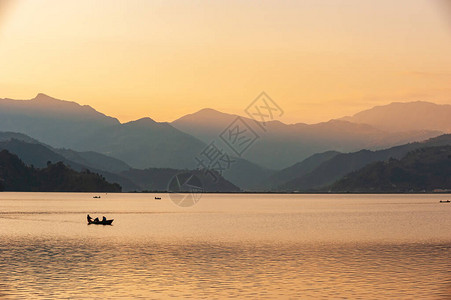 漂浮在有喜马拉雅山的晚上湖的小船剪影在背景中尼泊尔博卡拉图片