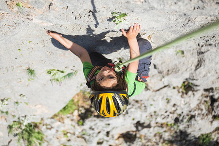 一个戴头盔的男孩在山上攀岩极度爱好运动健壮的孩子要坚强起来岩石爬的安全也非常高啊图片