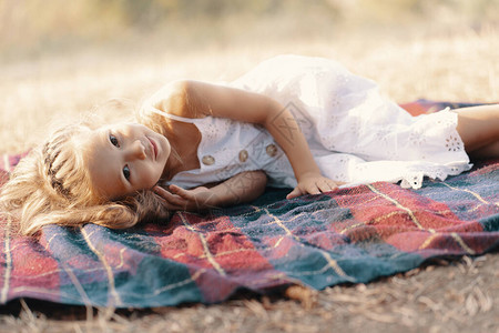 穿着白裙子的可爱无忧心女孩金发卷金躺在毯图片