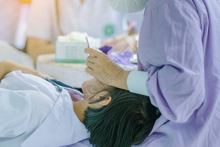 女牙医用口腔镜检查学生的牙齿并在学校图片