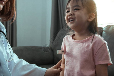 亚洲女医生正在使用温度计测量家中孩子的发烧情况校图片