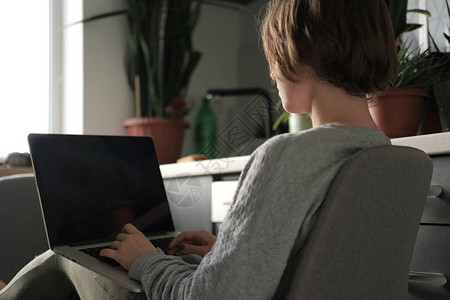 年轻的自由职业者在家工作女人看着笔记本电脑的屏幕隔离期间在家办公图片