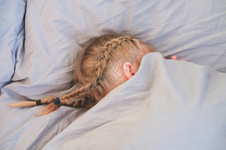 金发女孩躲在床单里孩子拒绝起床美丽的金发女孩早上躺在床上的背图片