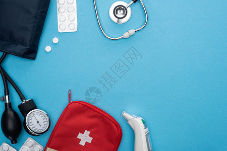 耳温计耳朵温度计充气袋中的药片血压计急救包和蓝底背景