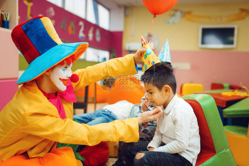 滑稽的小丑在小男孩头上戴了一顶帽子图片