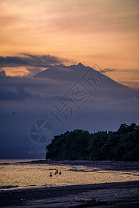 以橙色天空在日落时海中捕鱼的渔民背景是爪哇火山图片