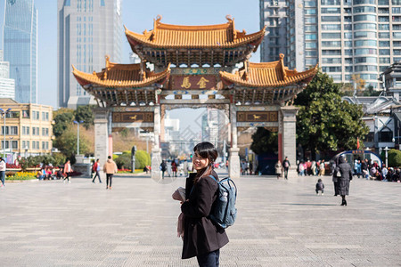 在金碧广场金马和玉鸡牌坊旅行的年轻女子旅行者图片