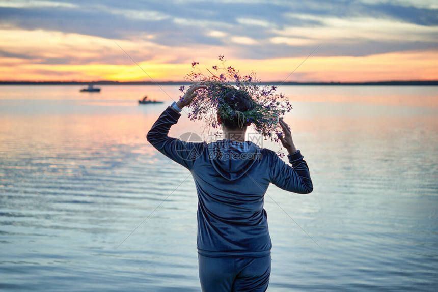 湖岸上带着野花环的女人在湖边的圣约翰前夜的一个晚上立陶图片