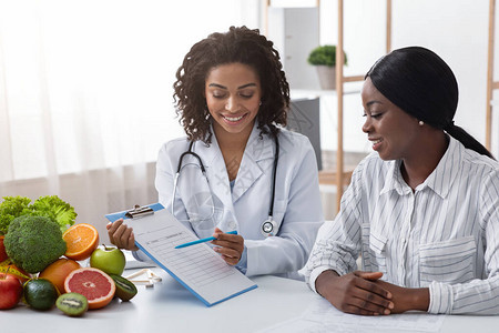 友好的非洲裔美国女营养师向患者解释新的治疗计划诊图片